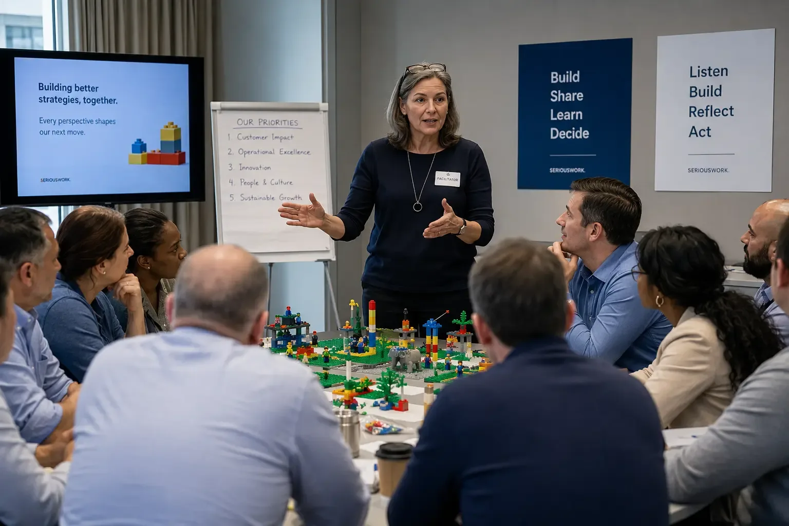 Experienced LEGO SERIOUS PLAY facilitator leading a professional workshop group around a shared landscape model