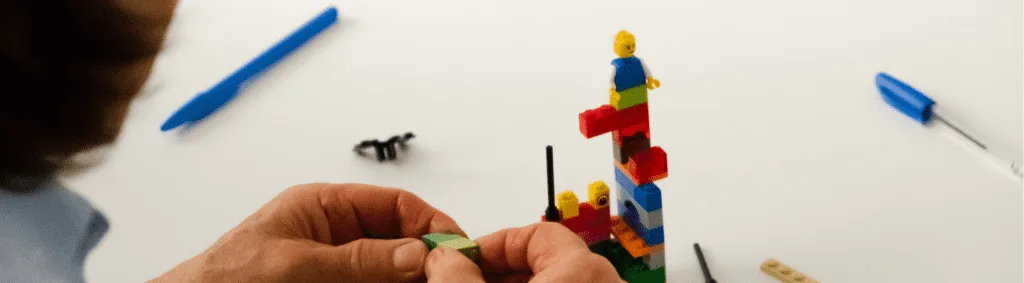A LEGO model showing a leader figure supporting and enabling a team.